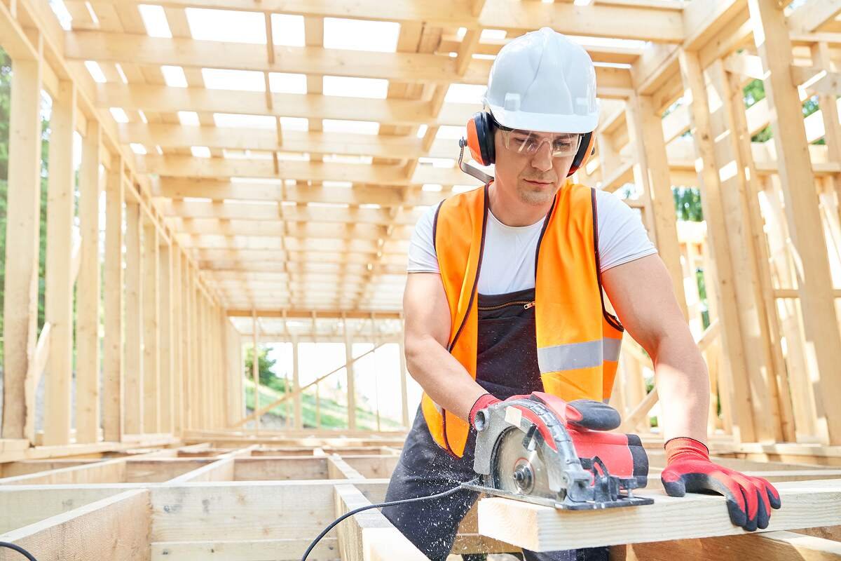 Constructor de casa cortando madera